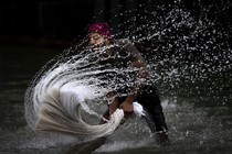 A person splashes water while washing clothes in a river.