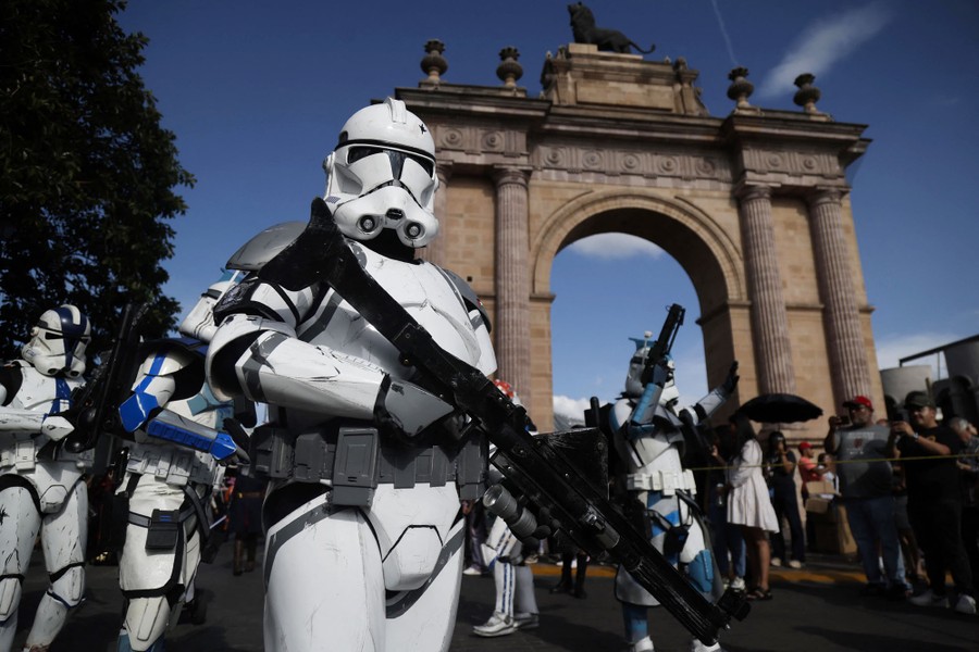 Several people in <i>Star Wars</i> stormtrooper costumes take part in a parade.