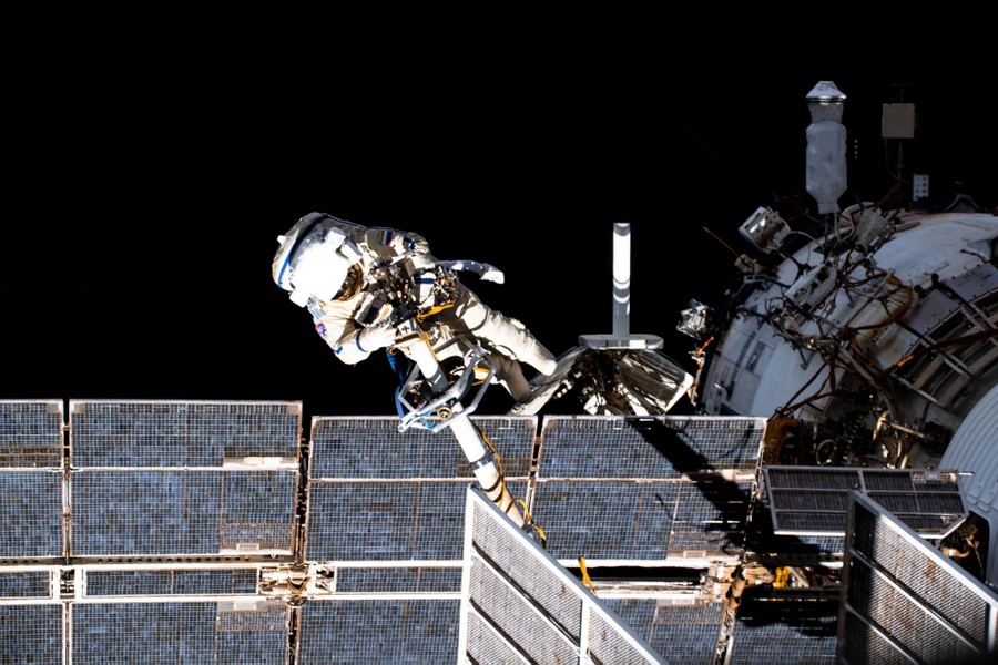 An astronaut works on equipment outside the International Space Station.