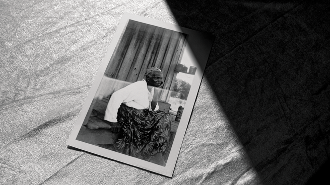 photo from the Federal Writers Project archive of a woman sitting outside a wooden house