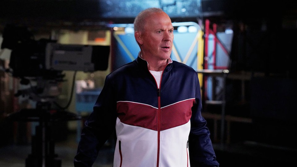 The actor Michael Keaton wears a blue, red, and white-colored tracksuit on the set of 'SNL'