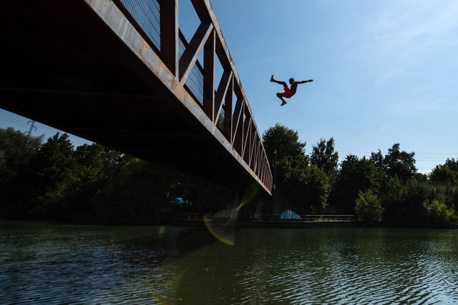 A man dives into a river from a bridge.