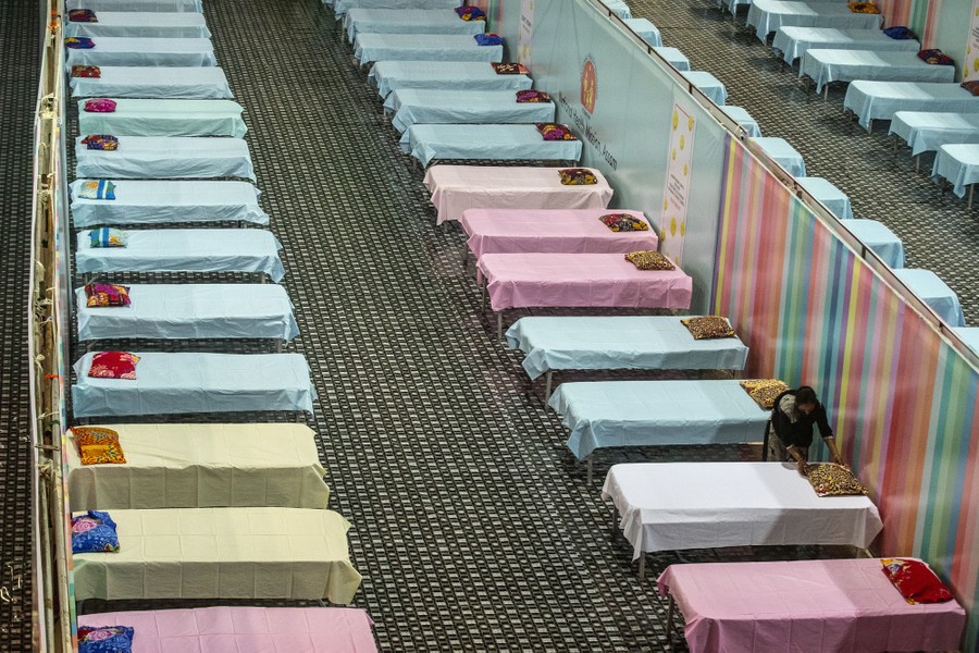 Rows of beds stand empty, awaiting patients, in a stadium.