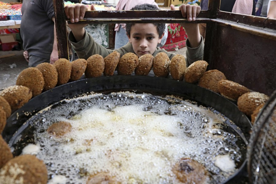 A boy watches closely as falafel is deep-fried.