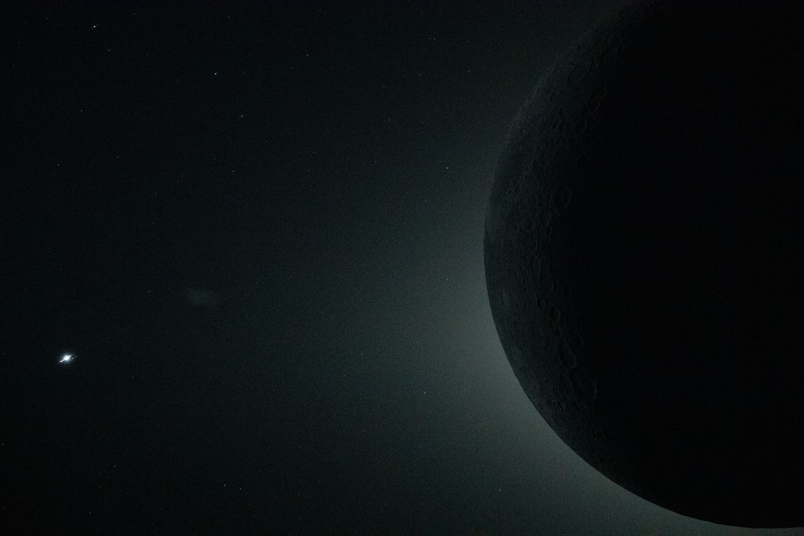 A close-up view of the moon, seen from the Orion spacecraft, during an eclipse, silhouetted against the glowing corona of the sun