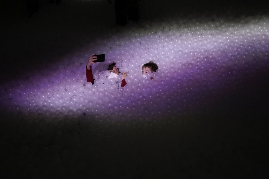 Two people buried in thousands of small plastic balls take a selfie.