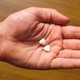 A hand holds two pills