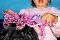 a child playing with a toy horse and carriage on her father's head