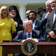 Trump sits at a desk surrounded by faith leaders