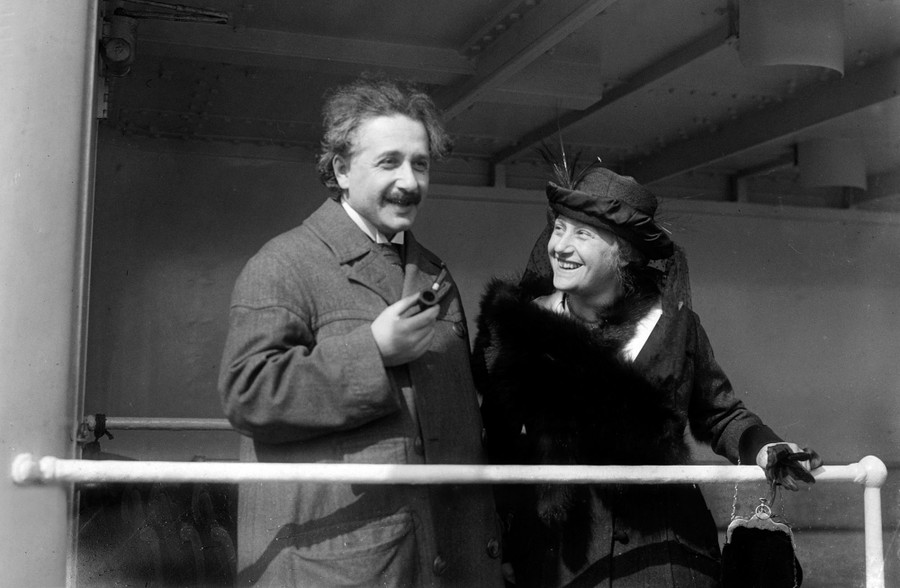 Albert Einstein stands beside his wife on a ship's deck.