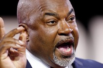 A color photograph of Mark Robinson speaking, and gesturing upward with his right hand