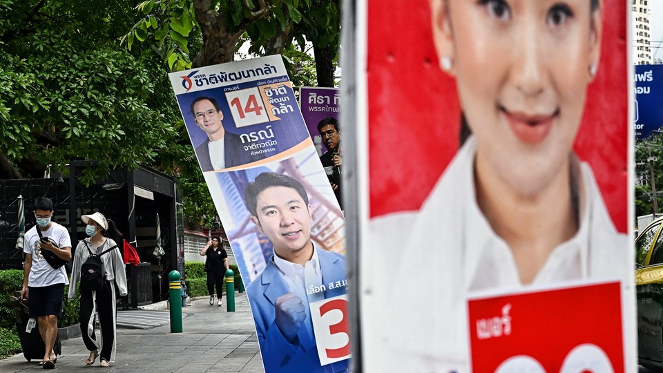 People walk past a campaign poster for opposition candidate Paetongtarn Shinawatra on a street in in Bangkok.