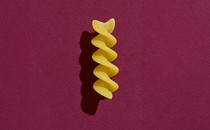 A piece of pasta on a purple background.