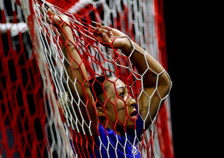 A soccer player leans against the back of the net after missing a goal.