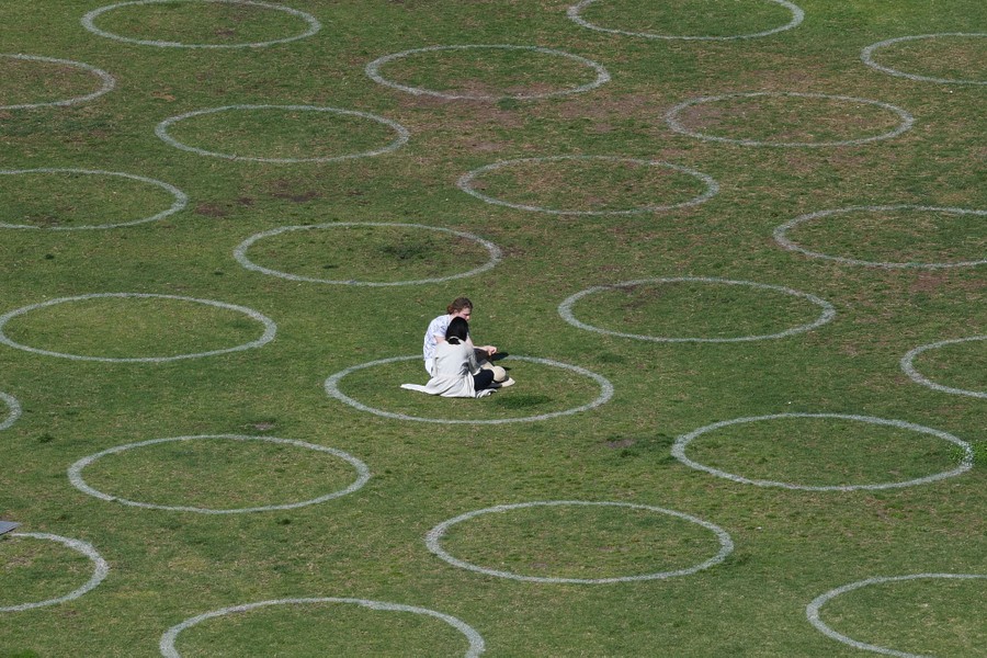 A couple sits on grass in one of many painted circles.