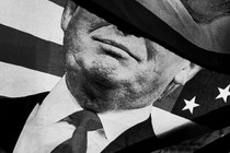 Black-and-white close-up of a billowing American flag featuring a picture of Donald Trump