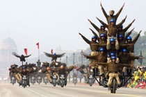 Several stunt teams ride in formations, with multiple people stacked up on single motorcycles.