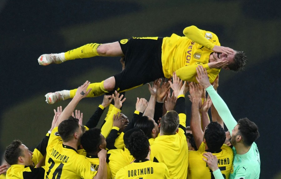Soccer teammates lift one of their own in celebration.