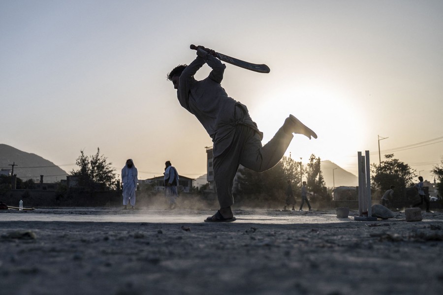 A person swings a cricket bat during a game.