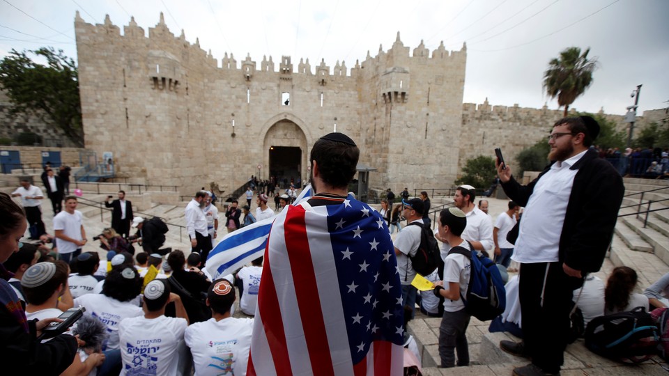 A man wearing an American flag in front of students waving Israeli flags