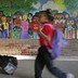 Two black children walk with backpacks past a mural depicting a diverse array of children.