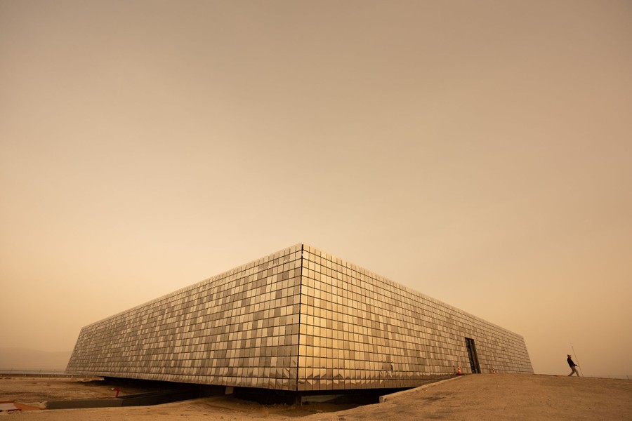 A low industrial building, clad in mirrored tiles, in a desert setting