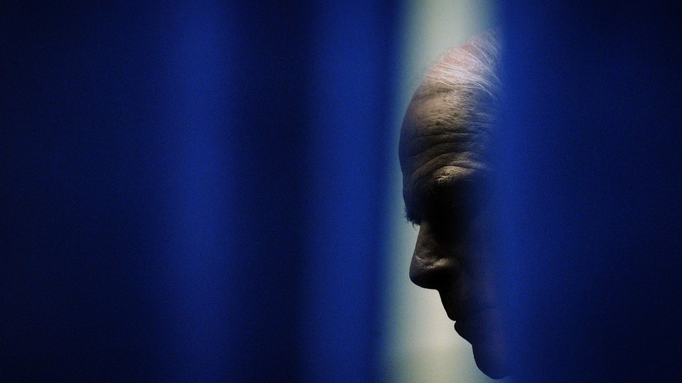John McCain is seen through a gap in blue curtains.