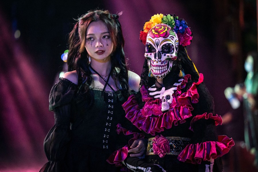 Two people in costumes walk on a street.