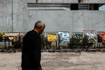 A man stands in the foreground as grocery carts filled with vegetables, canned food, and other perishables fill the background.