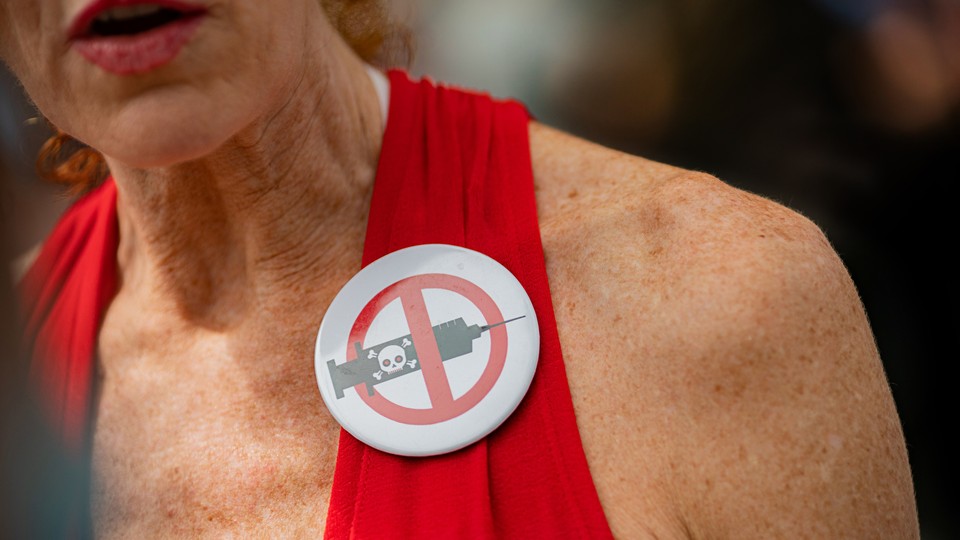 A woman wearing an anti-vax pin.