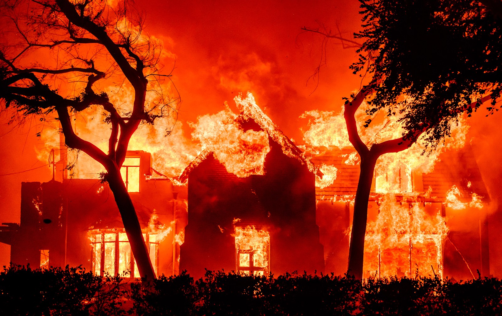A home is engulfed in flames during a wildfire.