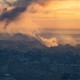 A rocket rises into a yellow, smoky sky from a darkened urban area in Gaza.