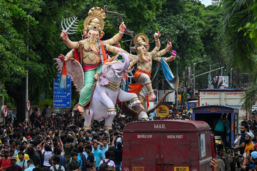 A crowd of people carry tall idols of the Hindu deity Ganesha.