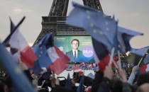 A crowd waves flags before a poster of French President Emmanuel Macron on the Eiffel Tower.