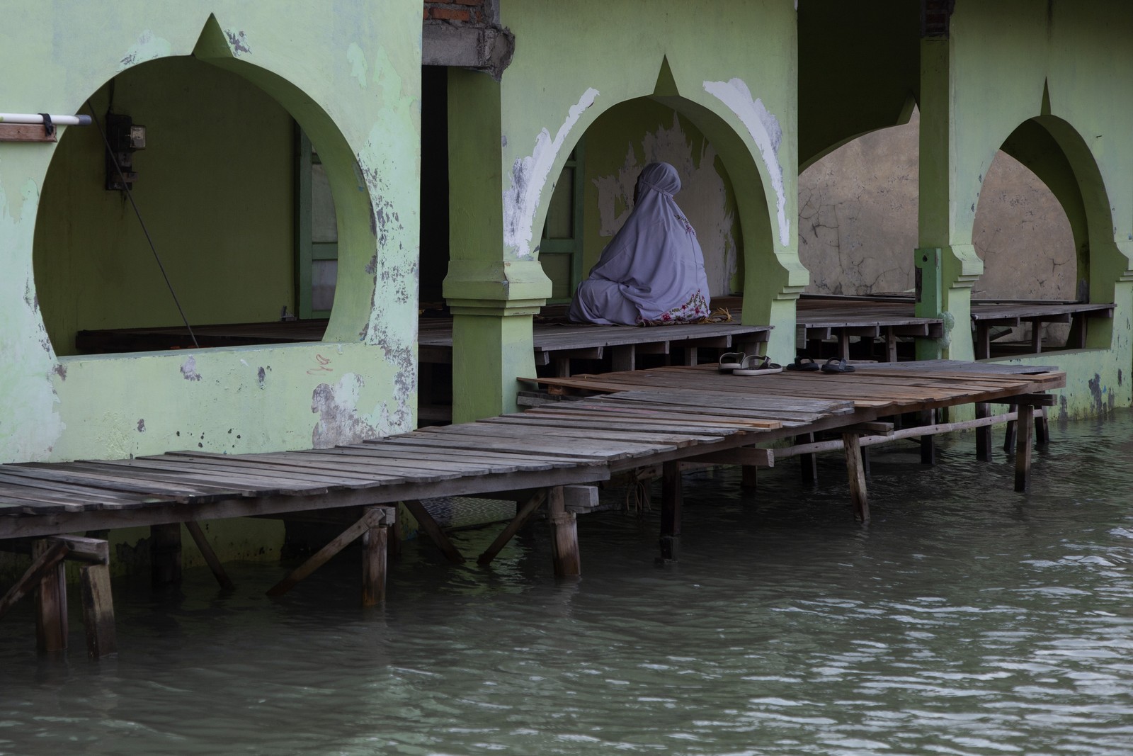 A woman prays on a platform in a mosque that has partially flooded.