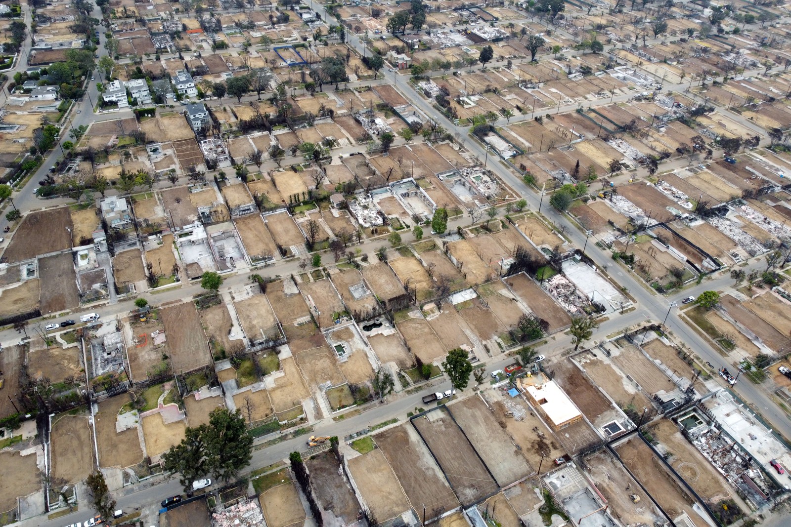 An aerial view of a residential neighborhood that is mostly empty lots, months after a wildfire.