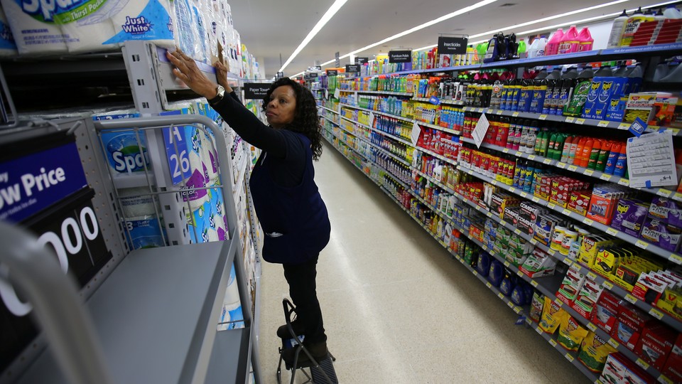 An employee places paper towels on a shelf at a store