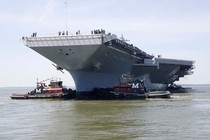 The Gerald R. Ford is maneuvered by tug boats in the James River