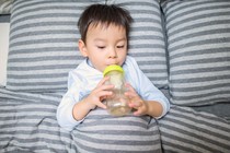 A toddler drinks from a bottle.