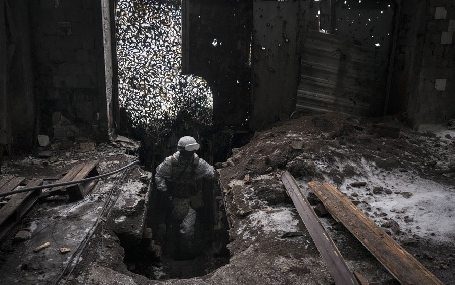 A soldier moves through the ruins of an industrial compound