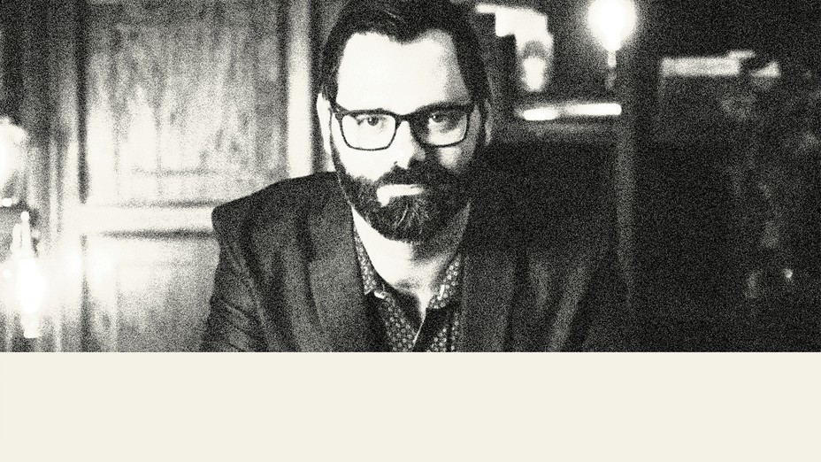 black-and-white photo of man with dark beard and glasses