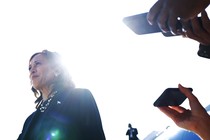 Reporters holding their phones out record Kamala Harris as she speaks to the press