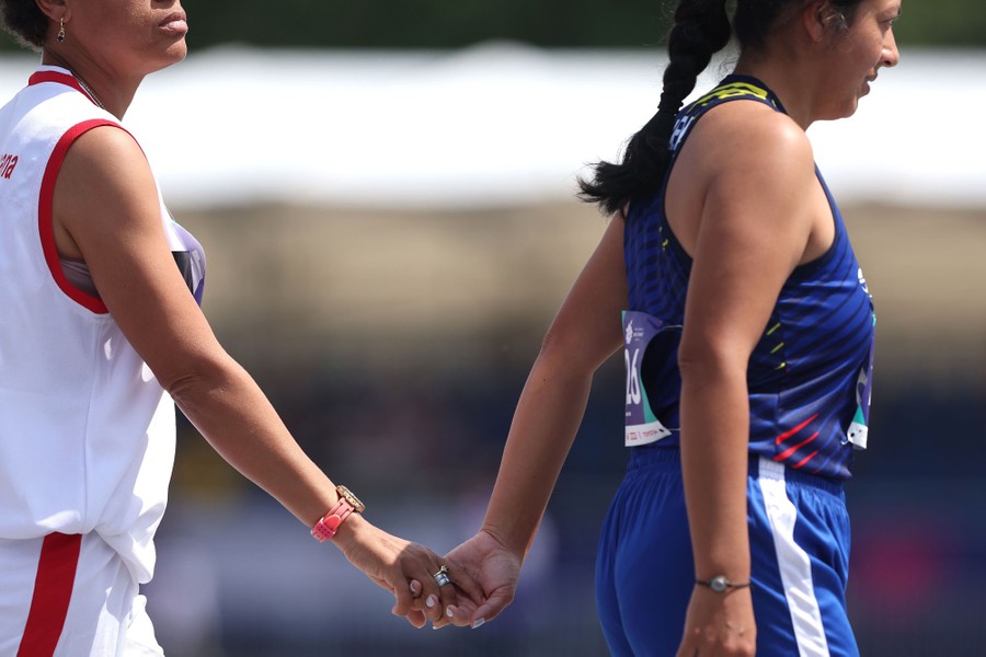 Two runners hold hands after a race.