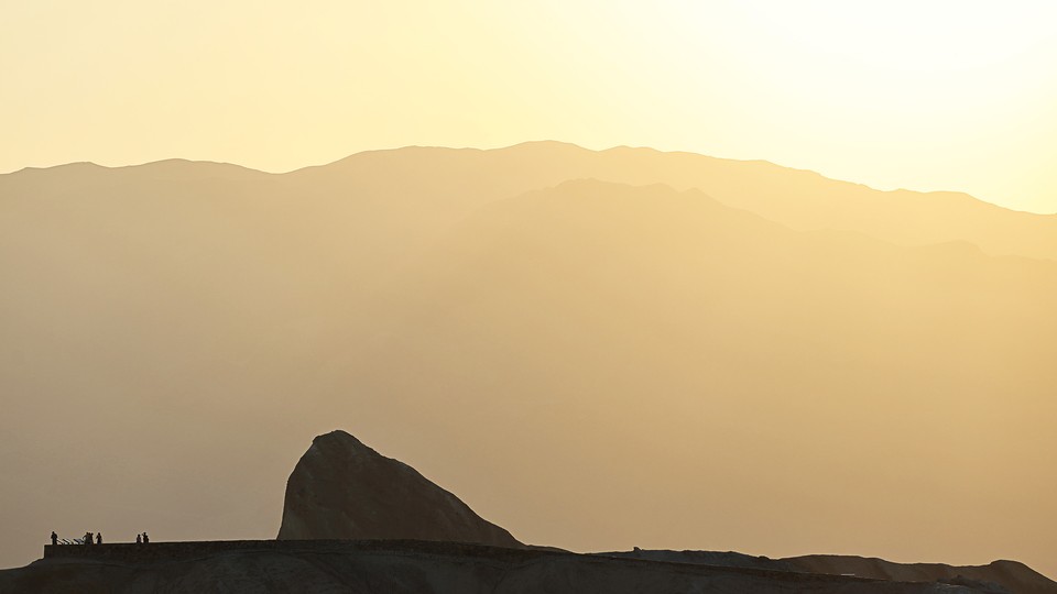 A Death Valley outcropping in front of a mountain, in hazy yellow heat