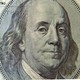 A close-up view of Benjamin Franklin's face on a $100 bill