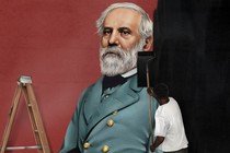 A man rolling black paint over a mural of Robert E. Lee