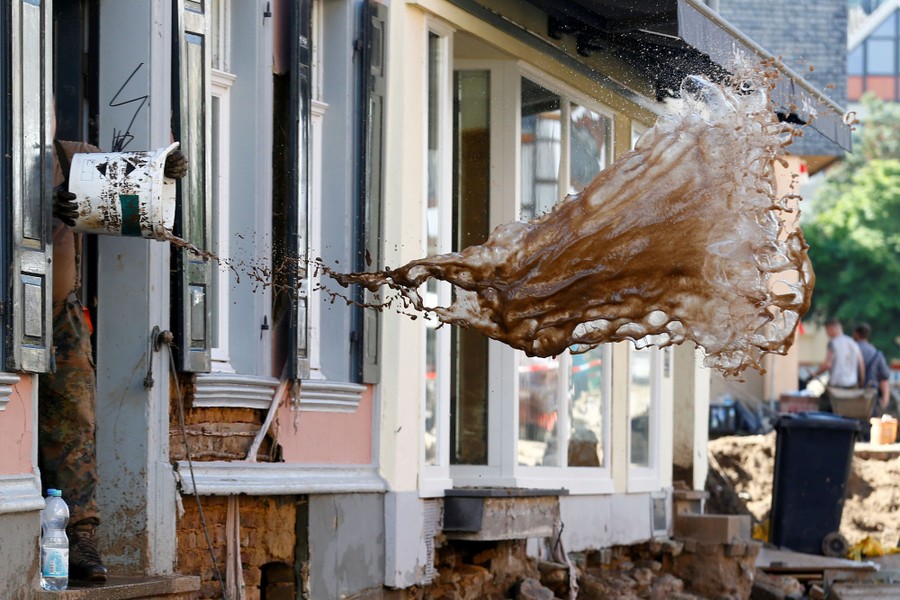 A person tosses a bucketful of muddy water out a door.