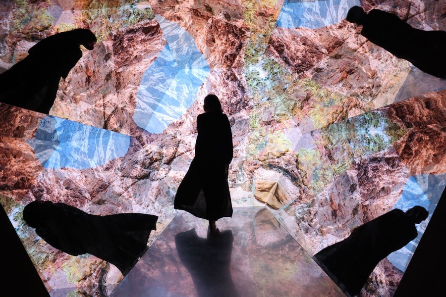 A person walks through a large immersive video installation.