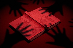 Shadowy hands reach for a book with a map of Europe on its cover