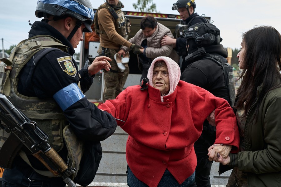 A woman is helped by soldiers and volunteers during an evacuation.